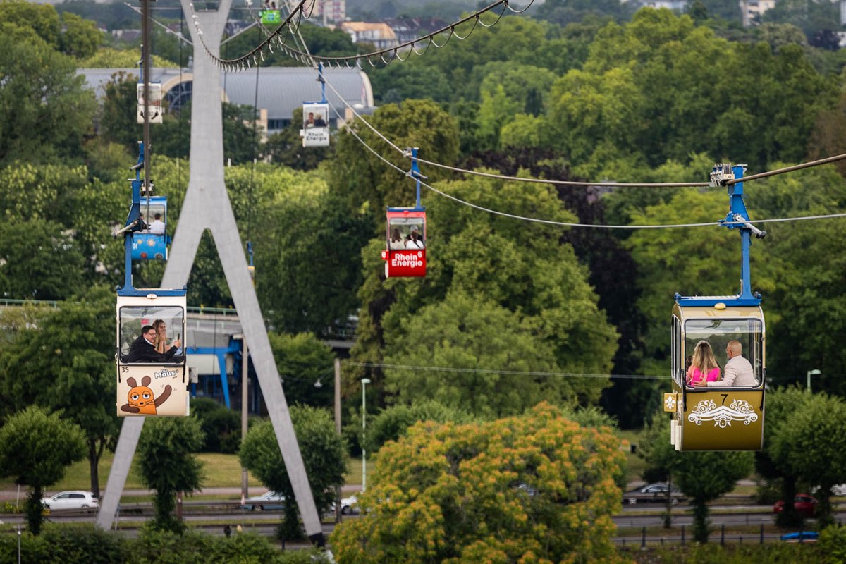 Kölner Seilbahn über dem Rhein, Hochzeitsgäste in gelber Gondel als außergewöhnliche Ambiente-Trauung